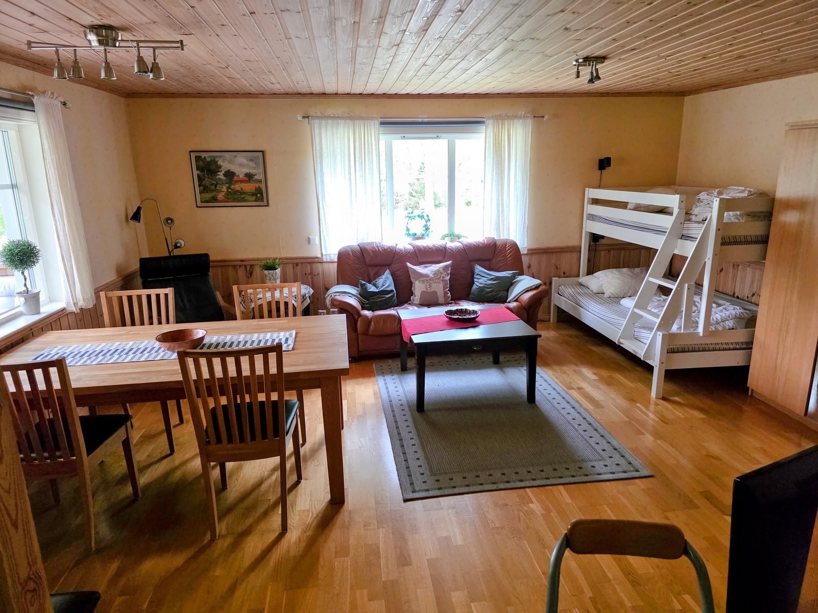 Allrummet med matbord för sex personer, soffa och våningssäng